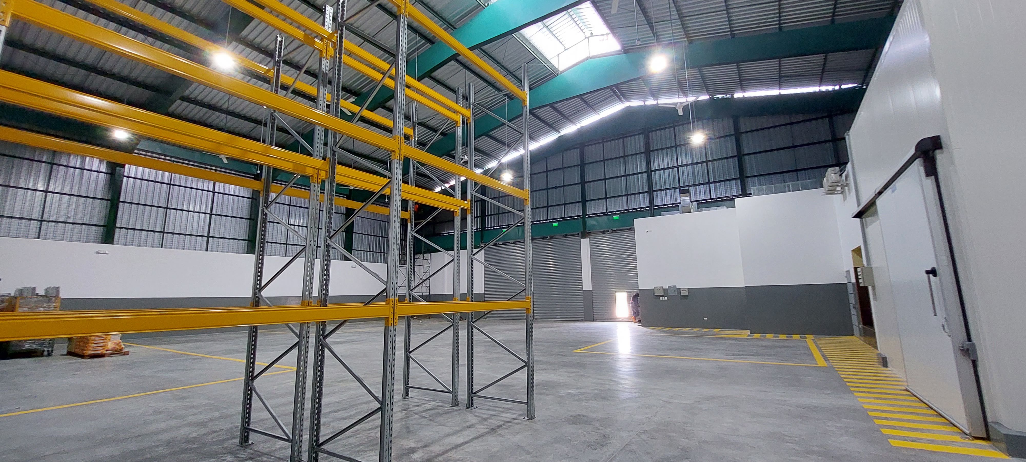Interior bodega con racks amarillos y cuarto frio