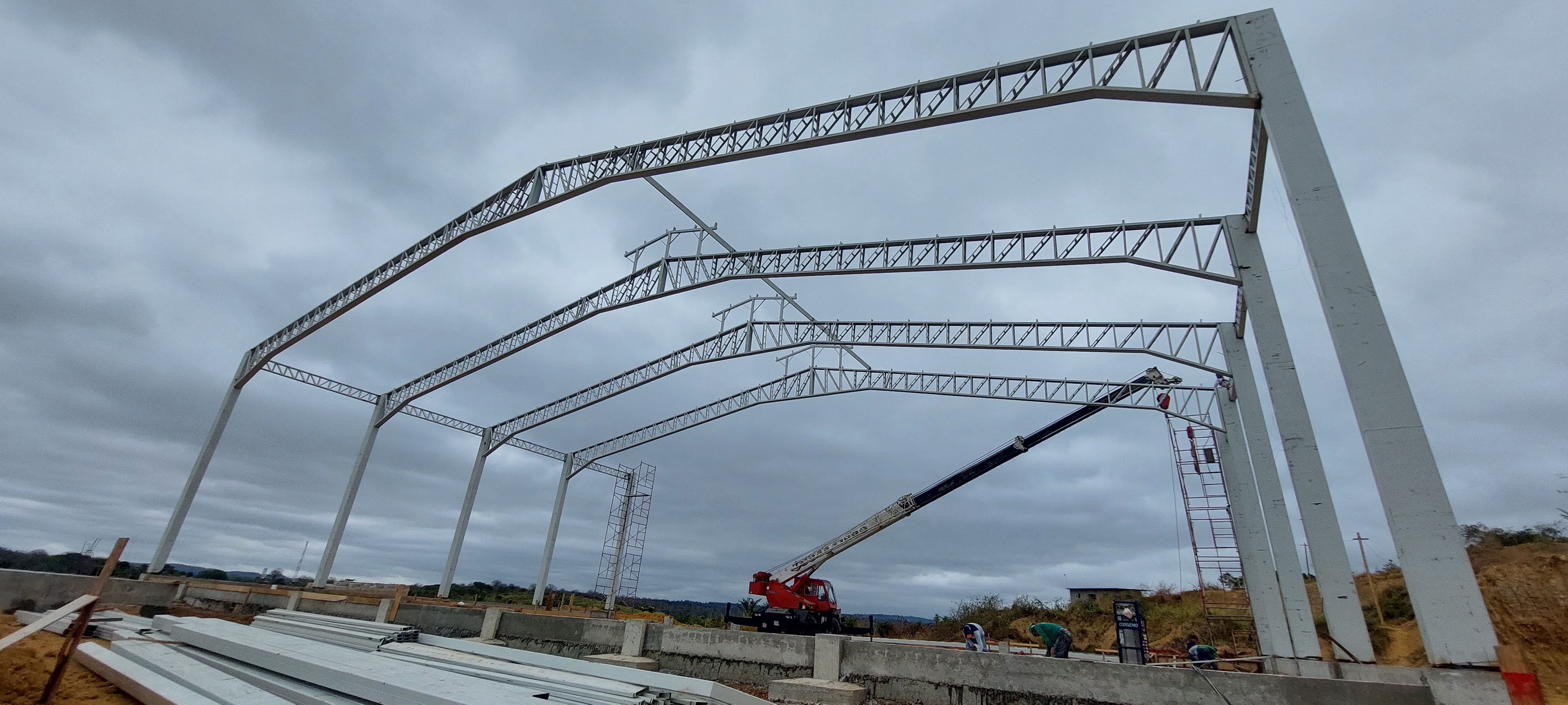 Montaje de cerchas con grua roja y andamios