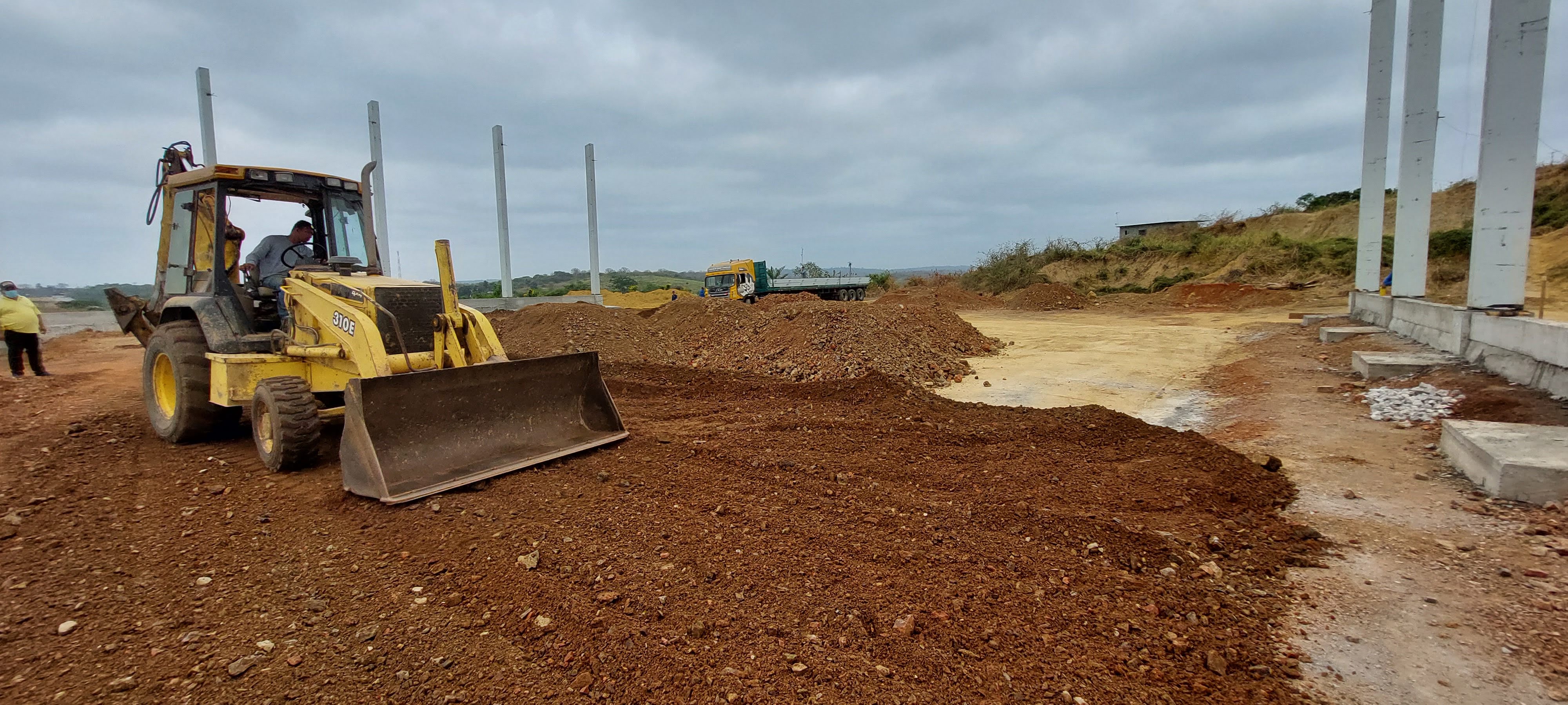 Retroexcavadora nivelando entre columnas prefabricadas