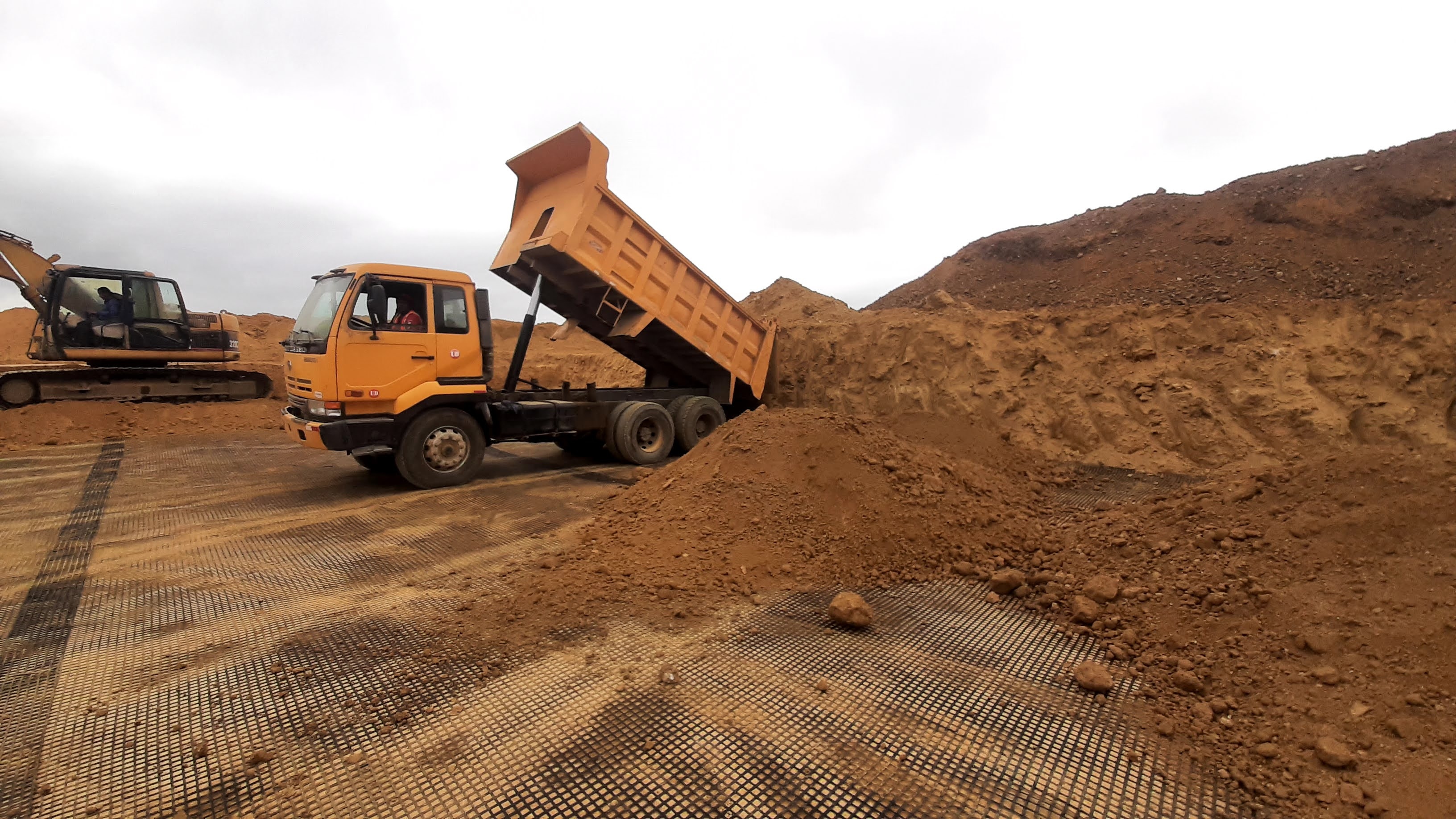 Volqueta descargando tierra sobre geomalla