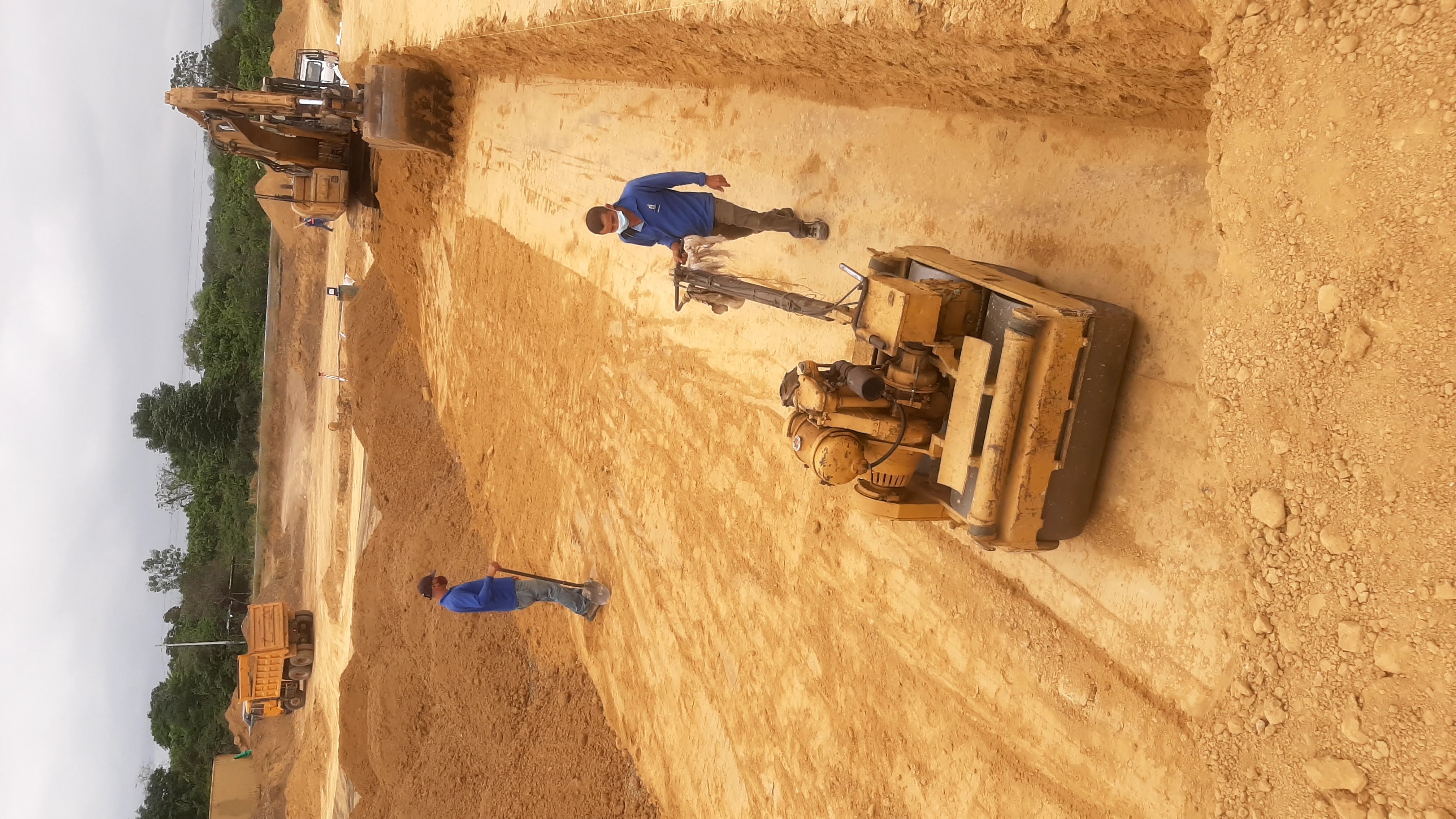 Tractor compactando terreno con trabajadores