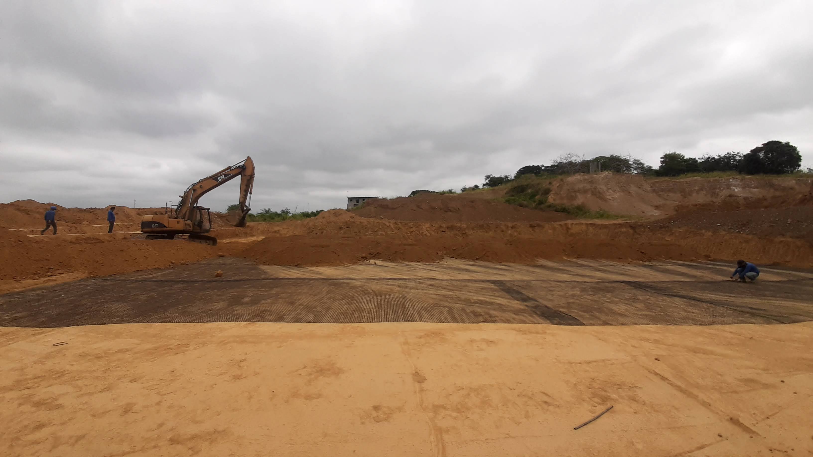 Excavadora sobre geomalla con trabajadores