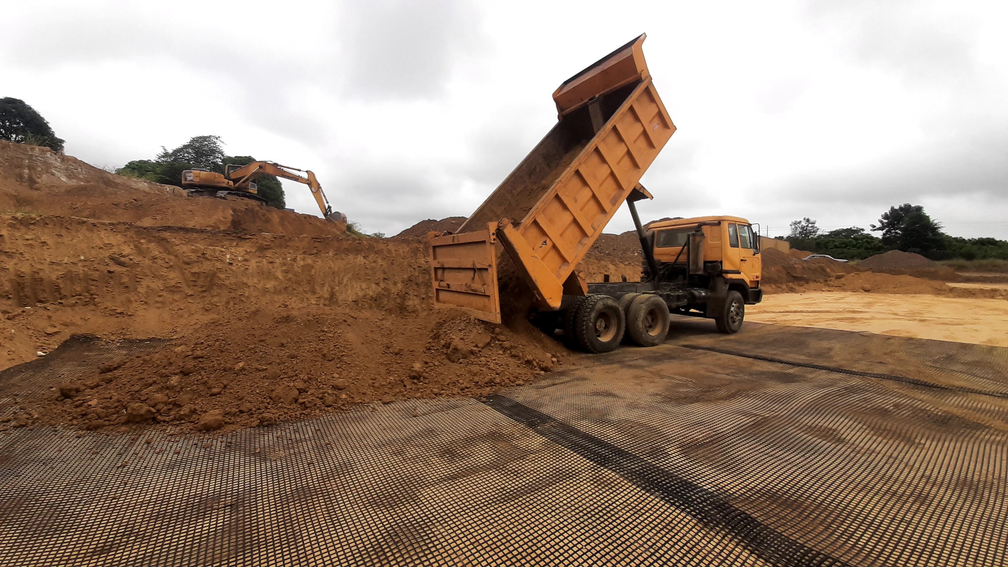 Volqueta descargando tierra con excavadora en talud
