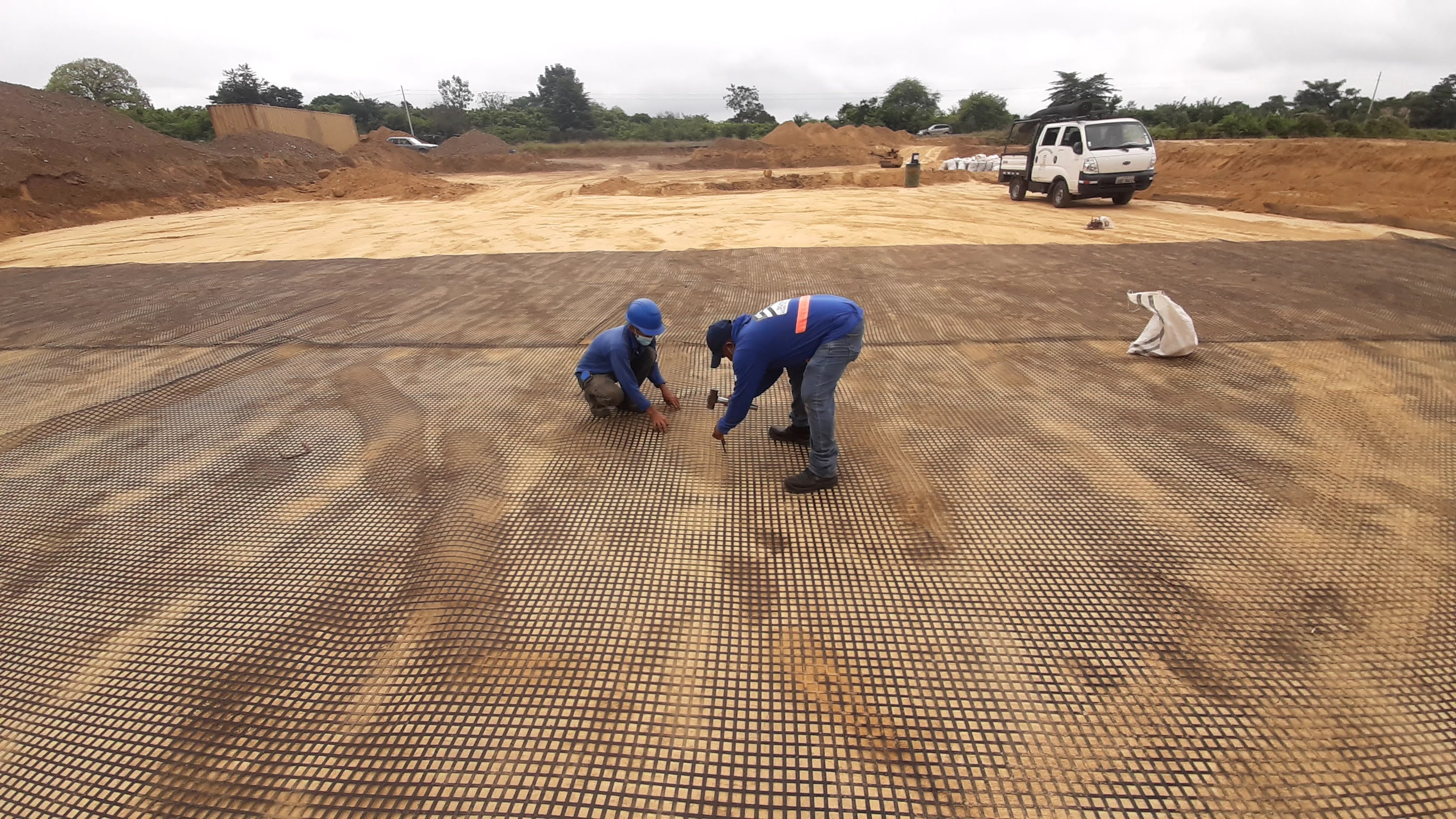 Trabajadores fijando geomalla en terreno