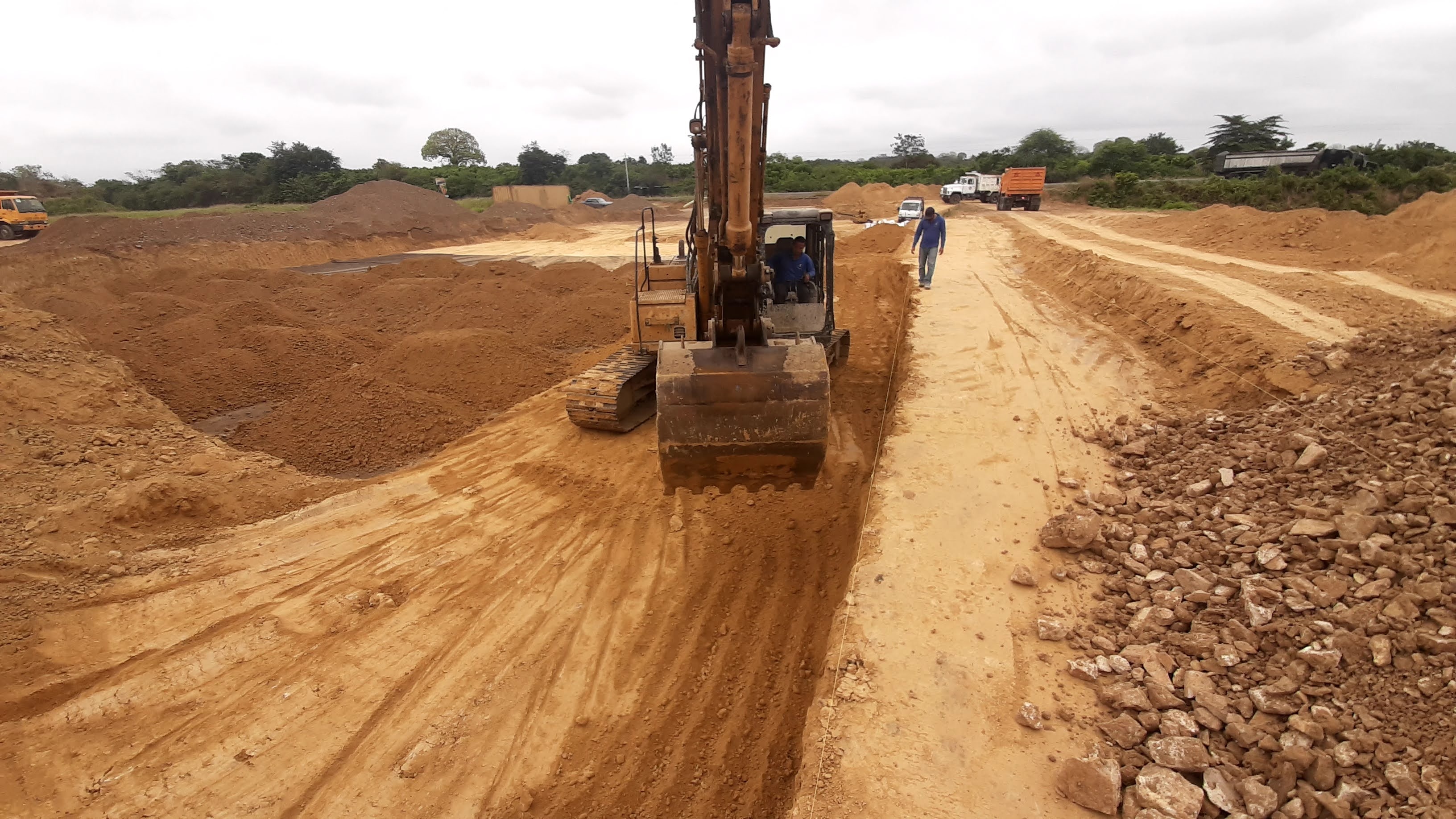 Excavadora en zanja con relleno de piedra