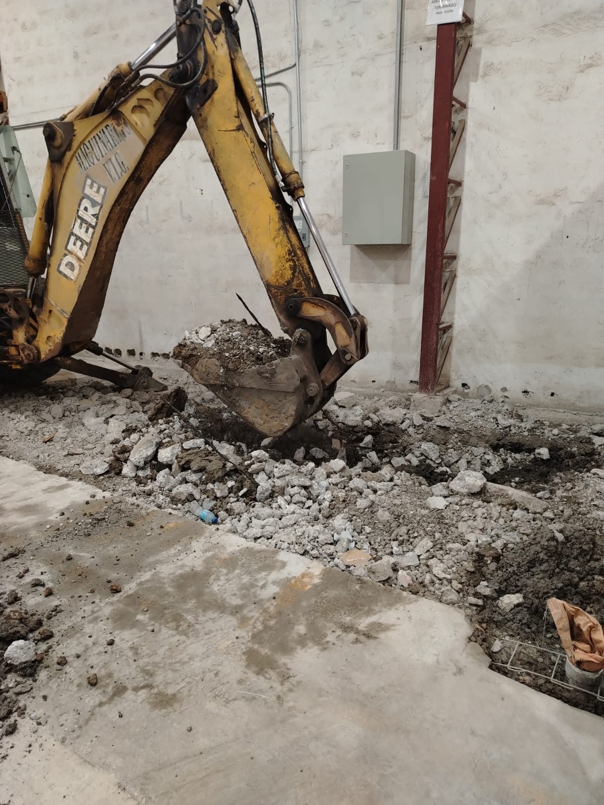 Retroexcavadora demoliendo piso de concreto