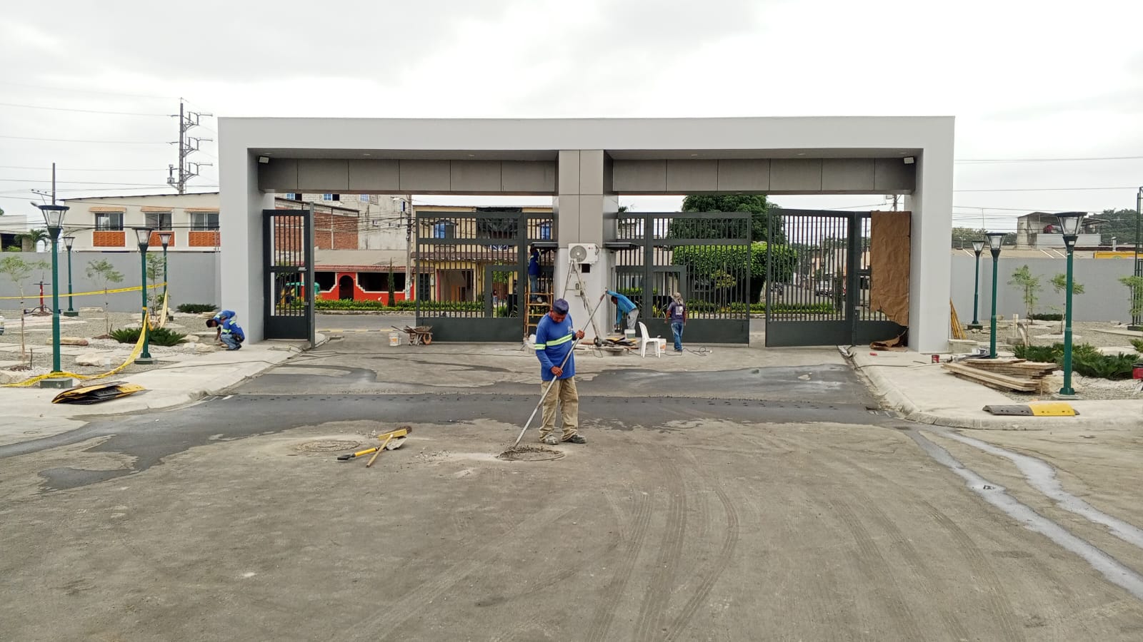 Entrada principal con porton metalico y trabajadores fundiendo piso