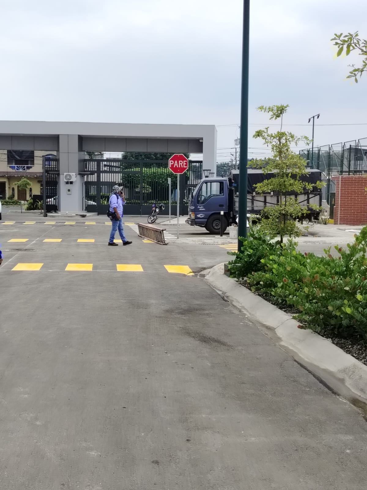 Vista interior hacia porton con senal PARE y paisajismo