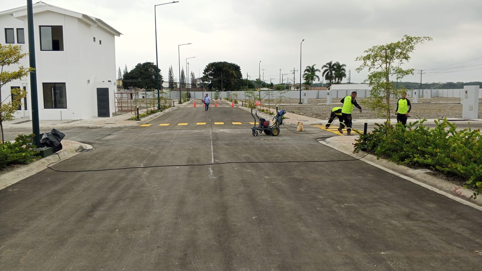 Calle principal con trabajadores pintando senalizacion vial