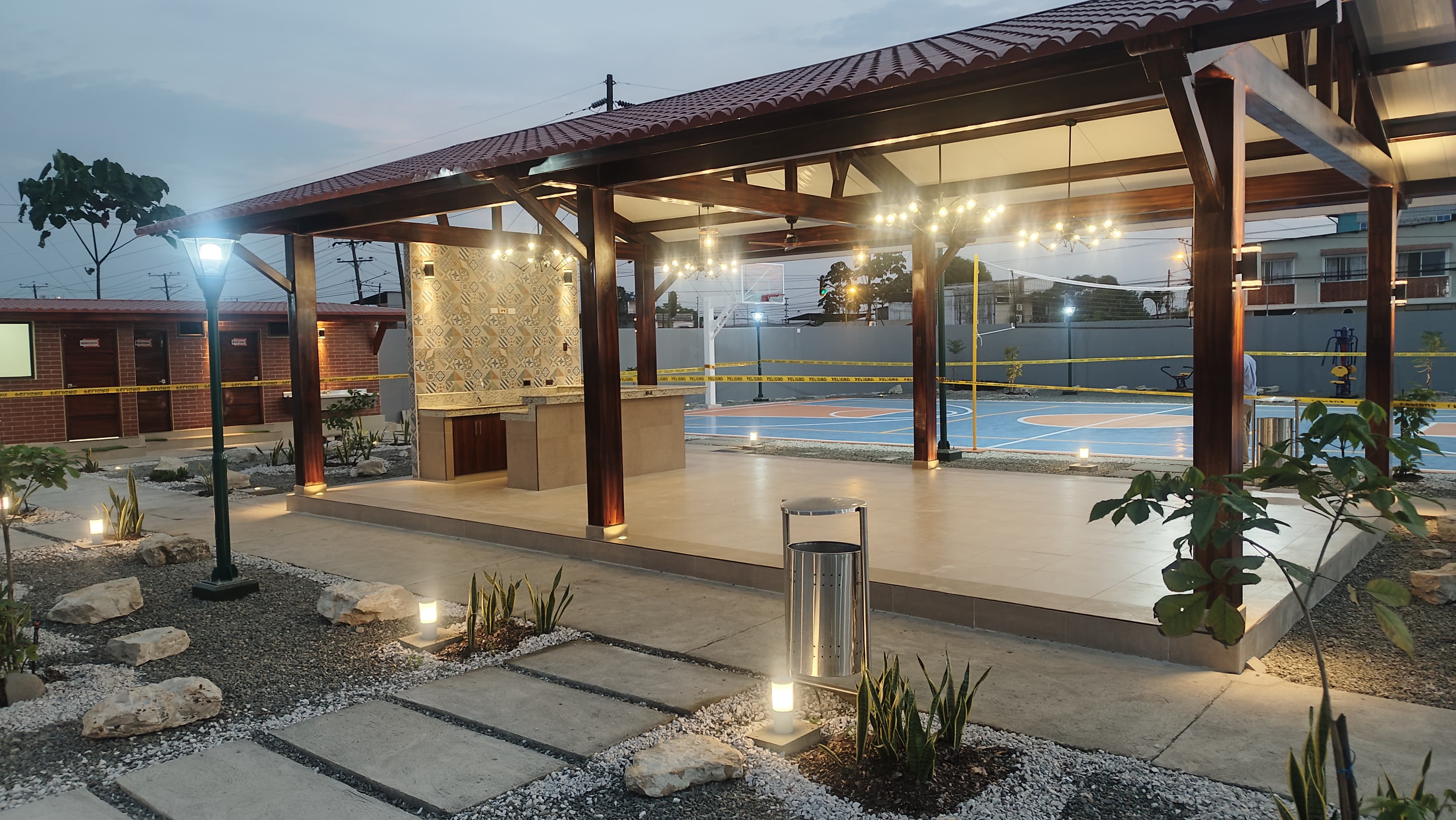 Pergola iluminada con area de BBQ y cancha al fondo