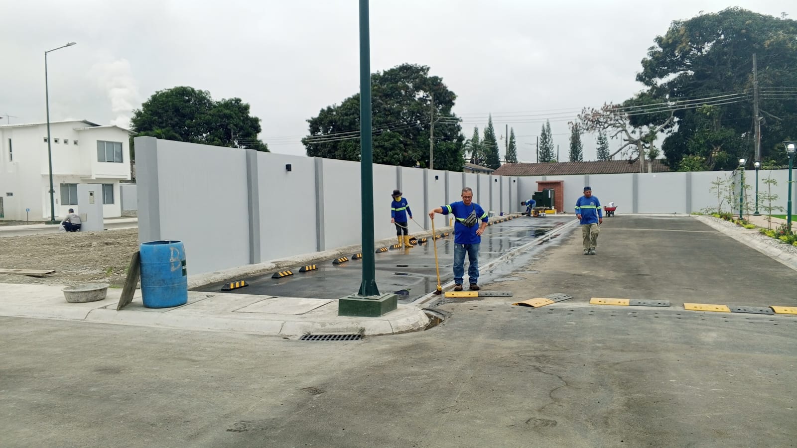 Trabajadores limpiando calle con topes y muro perimetral